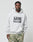 A man wears the LIVE FAST DIE YOUNG Live Fast Box Hooded in light gray with bold puffer print text and camouflage pants, standing against a plain background and looking at the camera. Made from hochwertiger Baumwolle.