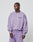 A man in the LIVE FAST DIE YOUNG Basic Purple Sweater and matching sweatpants, made from a cotton-polyester blend, stands against a light gray background, gazing to the side with a neutral expression.