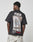 Wearing the LIVE FAST DIE YOUNG LFDY F*ck Phones Tee—an oversized black cotton T-shirt featuring bold white and red FUCK PHONES Live Fast Archive text and a back graphic—someone stands against a plain background.
