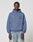 A man faces forward in a LIVE FAST DIE YOUNG LFDY GmbH Hooded with drawstring hood and chest print, paired with light blue faded jeans, against a plain gray background.
