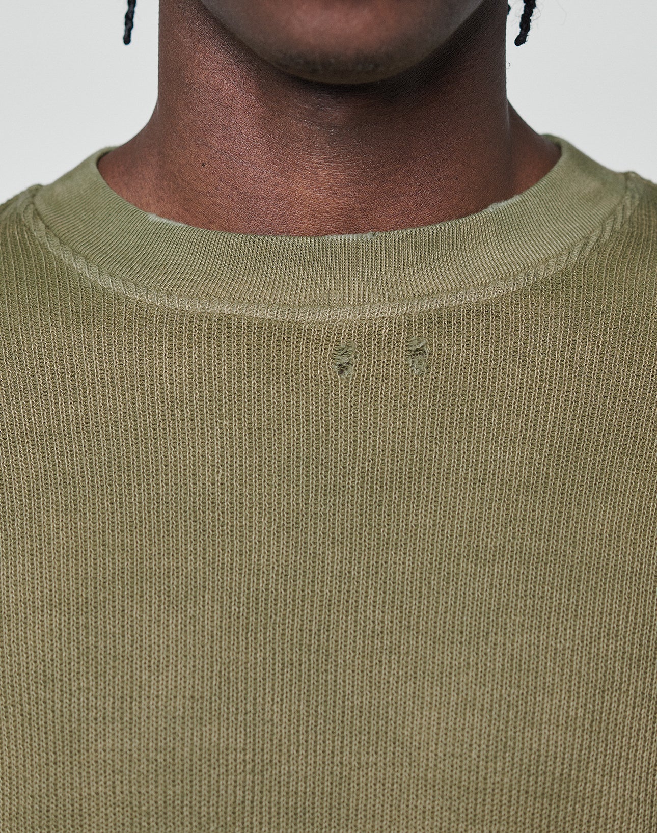 A close-up shows a person wearing the LFDY Rib Knit Longsleeve by LIVE FAST DIE YOUNG in olive green, 100% Baumwolle, Oversize Fit, with distressed details near the collar. Only the lower part of the face and neck are visible.