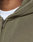 Close-up of a person wearing the LIVE FAST DIE YOUNG Basic Hooded Zip in olive green with a faded finish over a white tee. Visible zipper, fabric details, hood seam, and part of neck are shown.