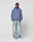 A person stands against a plain background wearing a blue LIVE FAST DIE YOUNG LFDY GmbH Hooded, loose-fitting faded jeans with Vintage Waschung, and white sneakers, hands in pockets with a neutral expression.