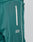 Close-up of the teal Live Fast Trackjogger by LIVE FAST DIE YOUNG, featuring a white zippered pocket, white piping, LIVE FAST embroidery on the upper thigh, and subtle Bügelfalte detailing for classic style.