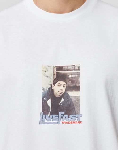 A close-up of the Cope South Bronx Tee by LIVE FAST DIE YOUNG, a regular fit white T-shirt in 100% cotton, with a photo print of a youth in a jacket and LIVE FAST TRADEMARK captioned below in bold blue and red.