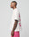A man in profile with short hair and visible arm and neck tattoos wears the LFDY Loyal Tee by LIVE FAST DIE YOUNG—an oversize white 100% Baumwolle T-shirt with pink front and back prints—and matching pink shorts against a plain background.
