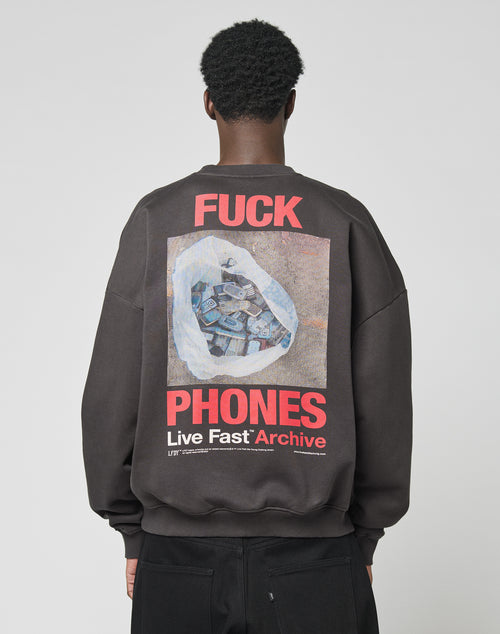 A person is seen from behind in the LFDY F*ck Sweater by LIVE FAST DIE YOUNG—an oversized black sweatshirt with bold red and white F*CK PHONES Live Fast Archive text and a hand holding phones graphic. Made from cotton and polyester.