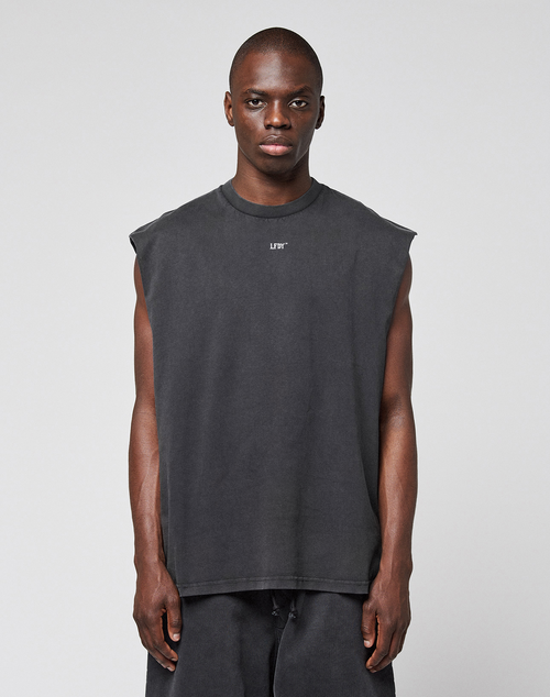 A person faces forward in an oversize fit LFDY Run Club Muscle Shirt by LIVE FAST DIE YOUNG, sleeveless and dark gray with matching pants, made from 100% Baumwolle and featuring a small white chest logo, against a plain light gray background.