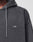 A close-up shows a person in the LIVE FAST DIE YOUNG LFDY Eagle Hooded sweatshirt, dark gray with an Oversize Fit and small white LFDY™ embroidery on the chest. Only part of their face and upper body is visible.