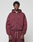 A man faces the camera in a maroon LIVE FAST DIE YOUNG Basic Hooded Zip with an oversized fit and matching sweatpants. Subtle branding details stand out against a plain, light gray background.