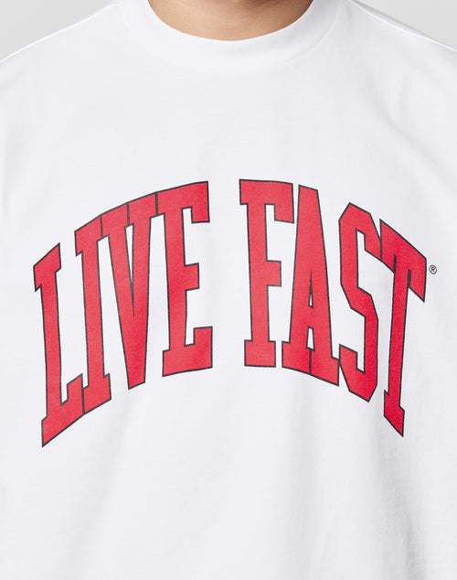 A person wearing the Live Fast College Tee, a white oversized shirt made from 100% Baumwolle, featuring large red LIVE FAST letters across the chest.