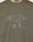 The Live Fast Rhinestone Tee by LIVE FAST DIE YOUNG features an olive green design with a large, silver rhinestone "LIVE FAST" logo across the chest. A tattoo on the bottom of a person's neck is visible at the top of the image.