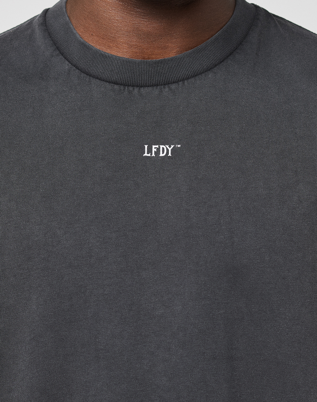 Close-up of a person wearing the LFDY Run Club Muscle Shirt by LIVE FAST DIE YOUNG, featuring white LFDY chest lettering. The shirt is made from 100% Baum­wolle and shown against a plain background.