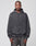 A person with short hair and a neutral expression stands facing forward in a dark gray LIVE FAST DIE YOUNG LFDY Eagle Hooded sweatshirt (hood down, oversize fit) and matching jeans. The background is plain light gray.
