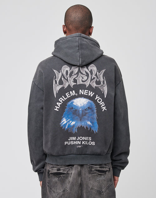A person wearing the LFDY Eagle Hooded by LIVE FAST DIE YOUNG in an oversize fit with a vintage wash. The back features a bold eagle graphic, HARLEM, NEW YORK text, and JIM JONES PUSHIN KILOS LITR. Crafted from soft cotton and shown from behind.