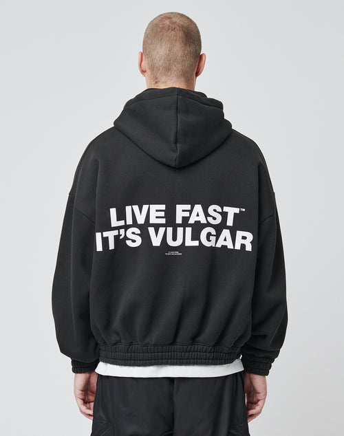From behind, a person with short hair wears the LIVE FAST DIE YOUNG LF Vulgar Hooded Zip in black, featuring an Oversize Fit and bold white LIVE FAST ITS VULGAR lettering on the back.