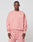 A man wearing a light pink LIVE FAST DIE YOUNG Basic Chest Sweater and matching sweatpants stands against a plain background. The cotton-blend sweatshirt features white text on the upper left chest. He faces the camera with a neutral expression.
