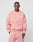 A man wears the LIVE FAST DIE YOUNG Basic Chest Sweater in an oversize pink fit, made from soft Baumwolle and polyester, paired with matching sweatpants. He stands against a plain light background, looking directly at the camera.