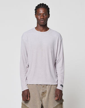 A man with braided hair wears the LIVE FAST DIE YOUNG LFDY Rib Longsleeve and loose tan pants, standing facing forward against a plain white background.