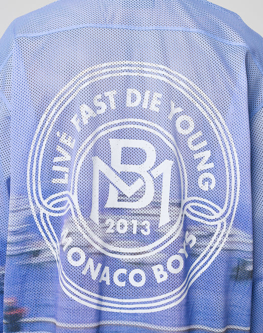 A close-up of the LFDY Yacht Jersey by LIVE FAST DIE YOUNG, a blue mesh oversized jacket with a white circular back logo reading LIVE FAST DIE YOUNG, MB1 2013, MONACO BOYS. Made from 100% polyester.
