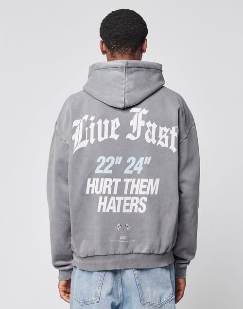 A person faces away, wearing a LIVE FAST DIE YOUNG LFDY Haters Hooded in oversize gray, featuring Live Fast, 22 24, and Hurt Them Haters boldly printed on the back in white and light blue.