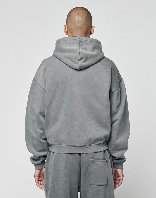 A person with a shaved head faces away from the camera, wearing the LIVE FAST DIE YOUNG Basic Hooded Zip in gray, paired with matching sweatpants against a plain light background.