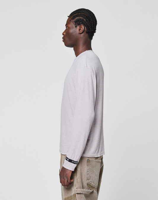 A person with braided hair stands in profile, facing left, wearing the LIVE FAST DIE YOUNG LFDY Rib Longsleeve in light gray and beige pants, set against a plain white background.