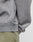 Close-up of a person wearing LIVE FAST DIE YOUNGs Basic Blank Sweater in light gray Oversize Fit, crafted from a Baumwolle-Polyester blend with ribbed hem and a small black and white tag near the side seam, paired with olive green pants.