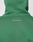 A close-up of the back of the Live Fast College Hooded by LIVE FAST DIE YOUNG in green, featuring small white "IM JUST A KID WITH A DREAM" text on top. Made from a soft Baumwolle polyester blend for lasting comfort; shown with hood up and oversize fit.
