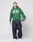 A person holds a basketball, wearing the green Live Fast College Hooded by LIVE FAST DIE YOUNG with a bold front print, oversized fit, baggy dark jeans, and white sneakers against a plain light background.