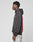 A young man stands in profile wearing the LIVE FAST DIE YOUNG LFDY Middlefinger Hooded, an oversize dark hoodie with red back text, paired with light gray patterned pants made from soft Baumwolle, against a plain light background.