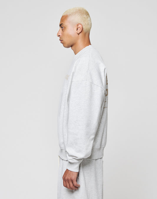 A person with short, bleached blonde hair stands in profile against a plain white background, wearing a LIVE FAST DIE YOUNG Basic Melange Sweater and matching sweatpants.