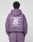 A person wearing a purple Basic Evidence Hooded and matching pants by LIVE FAST DIE YOUNG is seen from behind. The hoodie has “LiveFast” printed multiple times in white with a paper graphic, crafted from Baumwolle Polyester.