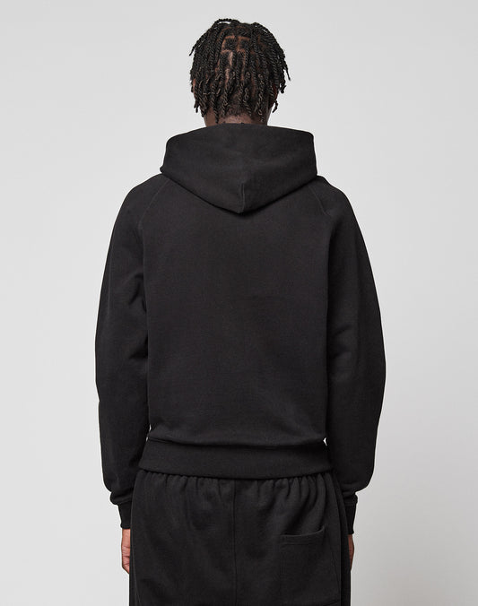 A person with braided hair stands with their back to the camera, wearing a black LFDY Embroidery Hooded by LIVE FAST DIE YOUNG and matching black pants against a plain light background.