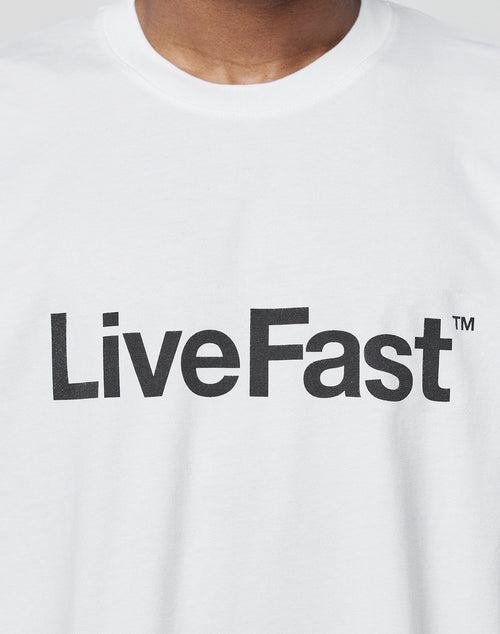 A person wears the Basic LiveFast Tee by LIVE FAST DIE YOUNG—white, regular fit, cotton t-shirt with “LiveFast™” printed in bold black letters across the chest.