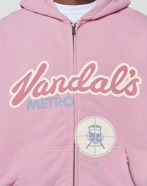 A close-up of the LFDY Vandals Hooded Zip by LIVE FAST DIE YOUNG—a pink, oversize-fit zip-up with bold "Vandals METRO" front print and a train-in-crosshair patch on the lower right.