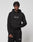 A young man with short braids models the LIVE FAST DIE YOUNG LFDY Embroidery Hooded and matching black sweatpants with white LiveVäst text, made from soft French terry, standing against a plain light gray background.