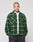 A person with a shaved head wears a green and black LIVE FAST DIE YOUNG LFDY Padded Flannel with chest pockets, layered over a white tee and black speckled pants, standing hands in pockets against a plain background.