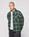 A person with a shaved head wears the green and black LIVE FAST DIE YOUNG LFDY Padded Flannel over a white t-shirt and black pants, standing against a plain light gray background.