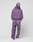 A person wearing a purple LIVE FAST DIE YOUNG Basic Wide Jogger set with an elastic waistband, a matching purple baseball cap, and white sneakers stands against a plain light background.