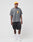 A man stands against a plain white background wearing a yellow baseball cap, black cargo shorts, white crew socks, white sneakers, and the LIVE FAST DIE YOUNG Melting Chest Tee—an oversize faded gray graphic t-shirt in vintage-washed cotton.