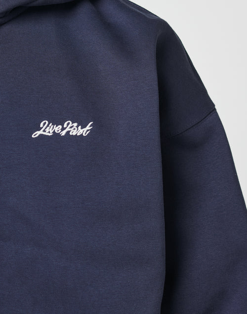 A close-up of the navy Basic Script Hooded Zip by LIVE FAST DIE YOUNG, showcasing “Live Fast” in white cursive on the chest and an Oversize Fit for a relaxed vibe.