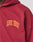 Close-up of the Live Fast London Hooded Zip by LIVE FAST DIE YOUNG in maroon oversize fit, featuring bold orange and yellow LIVE FAST lettering on the chest. Only part of the upper body is visible; crafted from soft Baumwolle.