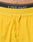 Close-up of LIVE FAST DIE YOUNG branding on the waistband of Live Fast Performance Running Shorts in bright yellow, featuring matching yellow drawstrings and partial view of a persons lower abdomen.