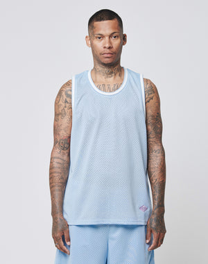 A man with short hair and tattoos faces forward, wearing a light blue LIVE FAST DIE YOUNG Basic Mesh Tank Top and matching shorts, against a plain light background.