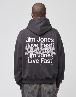 Wearing the LIVE FAST DIE YOUNG Live Fast NY Hooded in an oversize fit, made of 70% Baumwolle and featuring a bold “Jim Jones Live Fast New York” backprint, a person stands with their back to the camera against a plain backdrop.