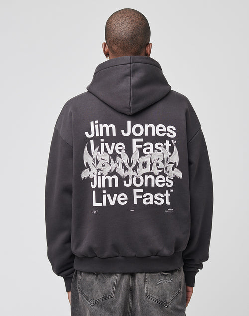 Wearing the LIVE FAST DIE YOUNG Live Fast NY Hooded in an oversize fit, made of 70% Baumwolle and featuring a bold “Jim Jones Live Fast New York” backprint, a person stands with their back to the camera against a plain backdrop.