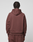 Seen from behind, a person with short, twisted hair wears the LIVE FAST DIE YOUNG LFDY Embroidery Hooded in brown with matching pants, both made from soft French Terry, set against a plain light gray background.