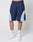 Someone is wearing LIVE FAST DIE YOUNG Basic Trackshorts in navy blue with light blue and white panels, featuring an elastic waistband, paired with white LEDY socks and white sneakers, standing against a plain light background.