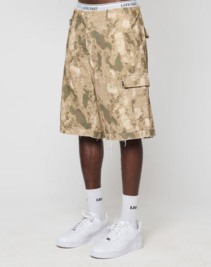 A person wears beige and green LFDY Cargo Shorts by LIVE FAST DIE YOUNG, white LIVE FAST waistband underwear, white LFIV socks, and white sneakers. Only the lower body is visible against a plain background.